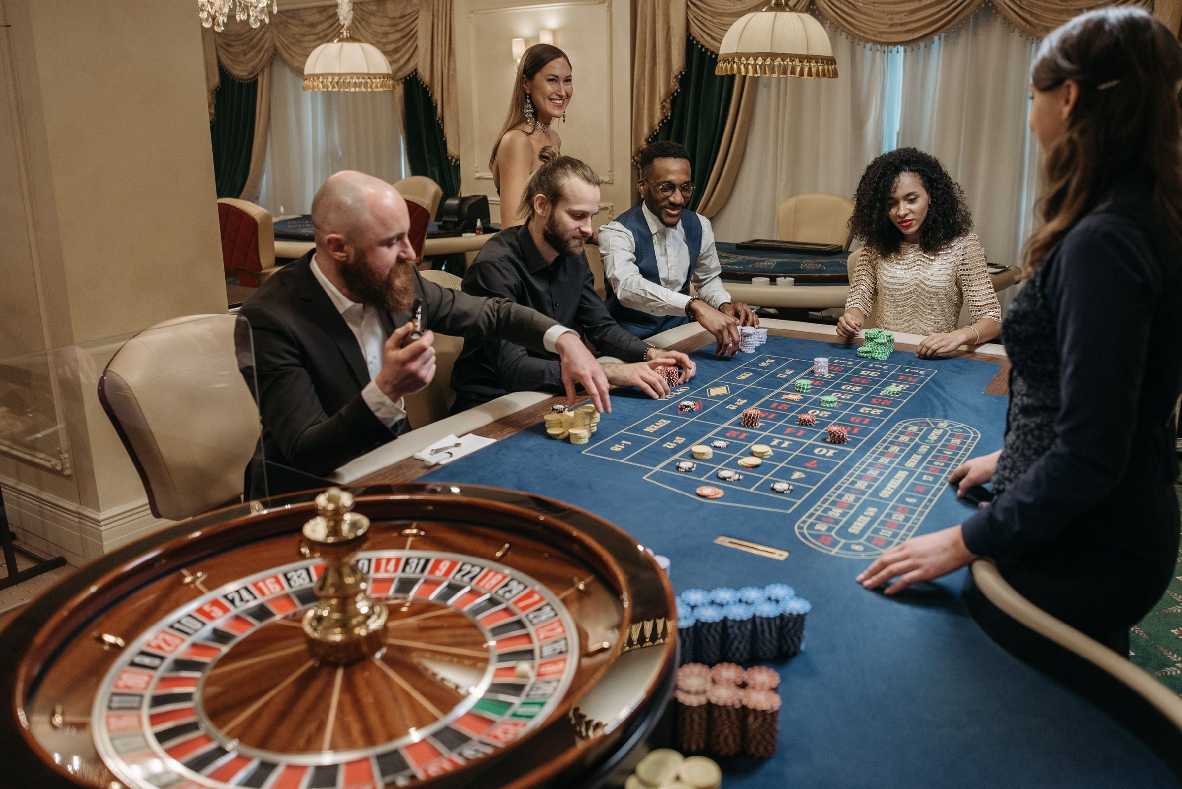 Gäste und Croupier an einem Roulettetisch in einem Casino-Salon am Abend